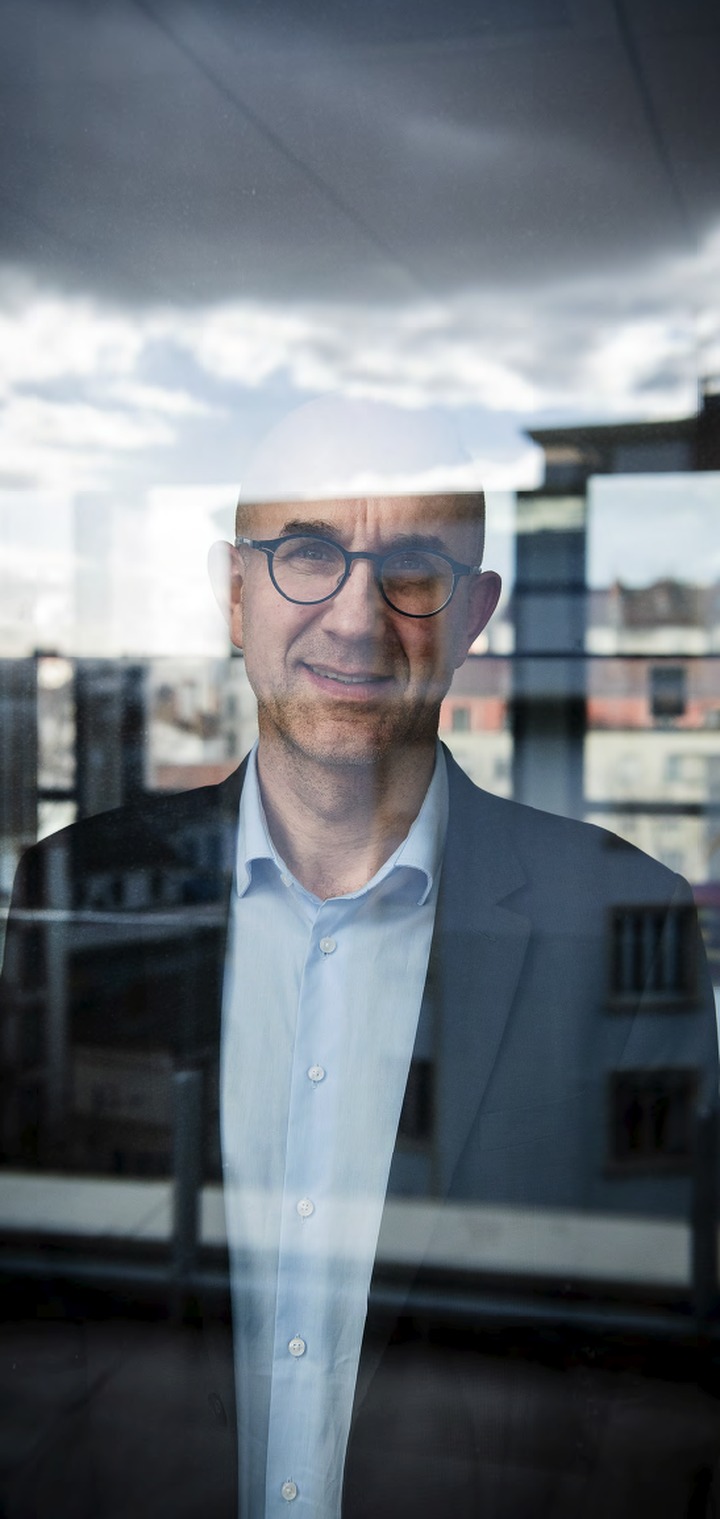 Portrait d'un dirigeant derrière une vitre où se reflète la ville